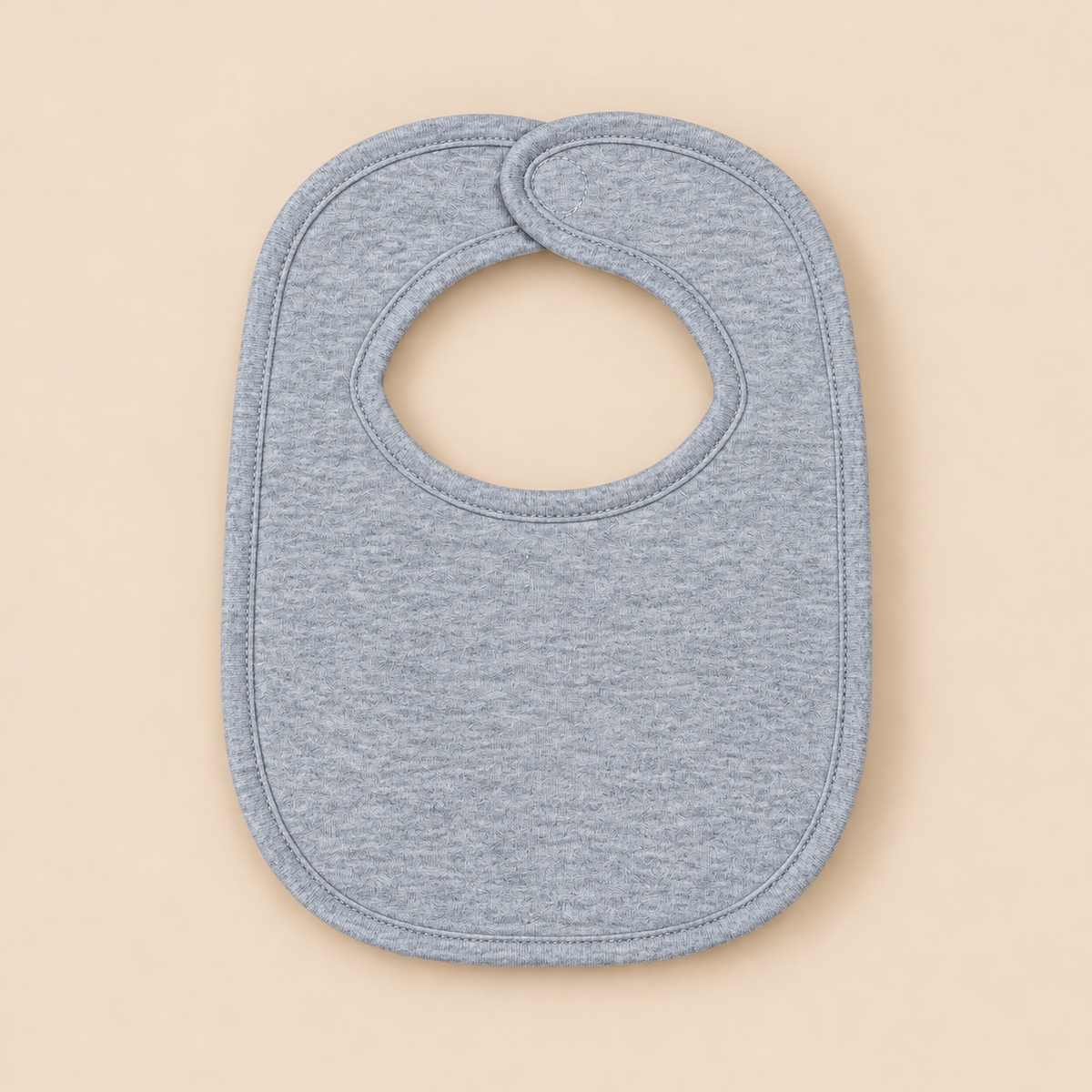 A light heather gray baby bib with a rounded shape and a neck opening, shown flat on a solid beige background.