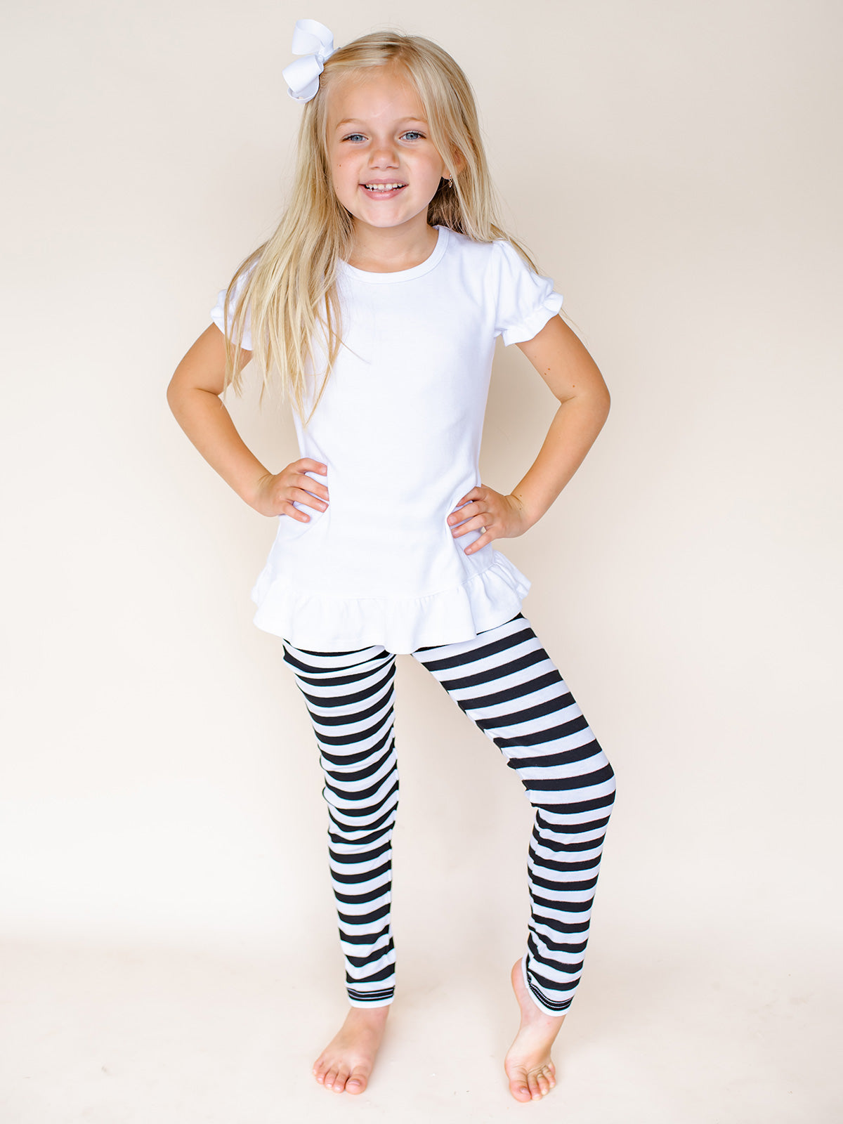 Girl wearing black and white striped leggings from ARB Blanks -- 95% cotton spandex blend, embroidery and HTV ready, sizes 12M to 10
